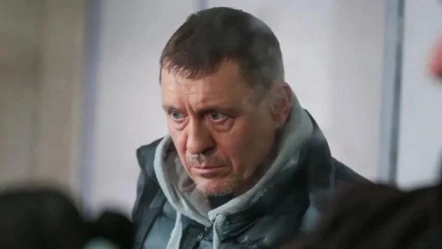 Мужчина средних лет с бородкой и усами, заметными морщинами и отеками под глазами