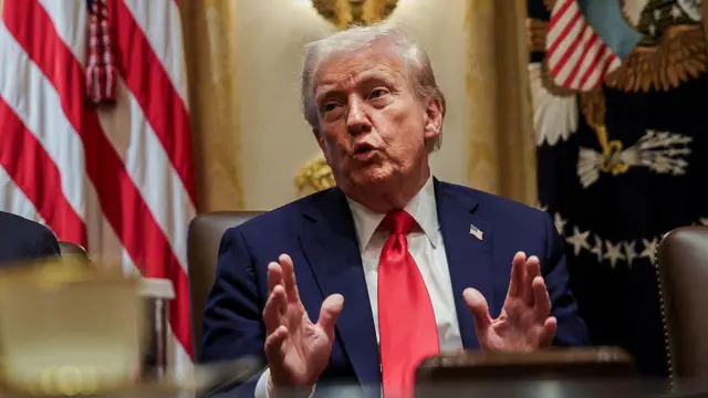 Donald Trump kırmızı kravat takmış. Ellerini de kullanarak konuşuyor