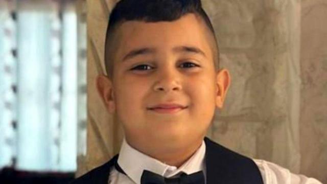 Uma foto do álbum de família de Adam, de oito anos, que foi baleado por militares de Israel, posando de gravata borboleta e colete