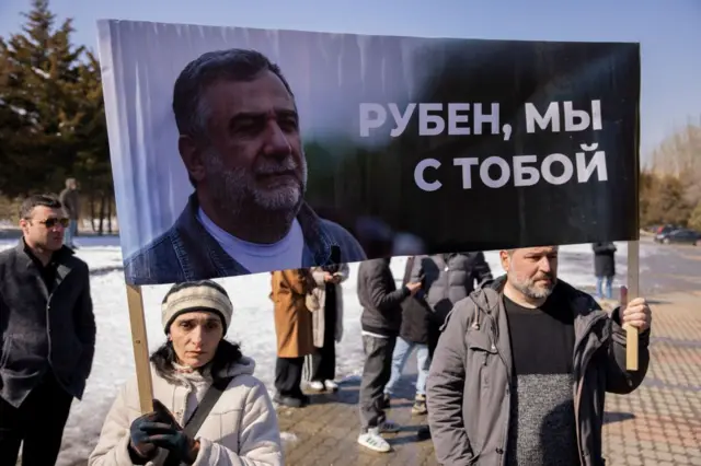 Митинг в поддержку Рубена Варданяна: мужчина и женщина держут плакат с большой фотографией Варданяна и надписью "Рубен, мы с тобой"