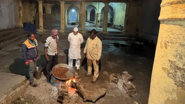 हेड शेफ और उनकी टीम जर्जर रसोईघर परिसर में कबाब पकाते हुए