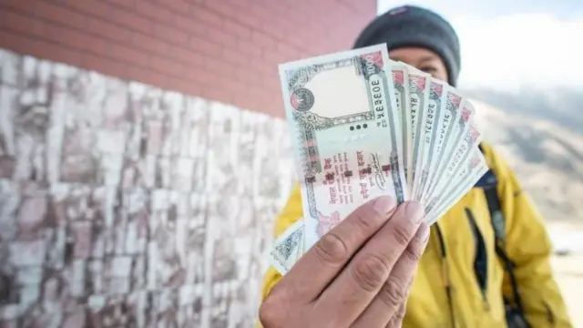 हातमा पैसा बोकेका एक पुरुष