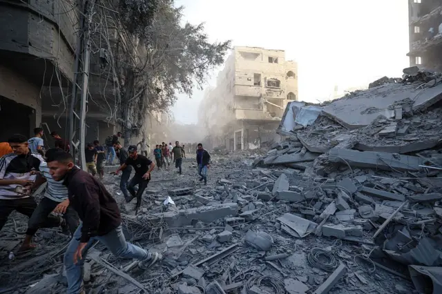 غزيون يهرعون للاحتماء بعد غارة إسرائيلية استهدفت مبنىً في مخيم البريج للاجئين الفلسطينيين وسط قطاع غزة في 19 أكتوبر/تشرين الأول 2025