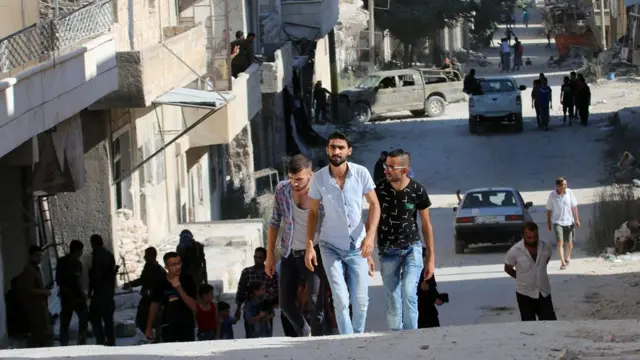 Residentes caminan por un barrio de Alepo.