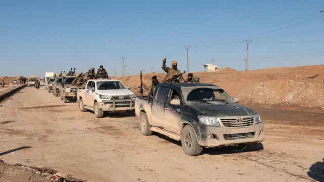 toprağa bulanmış yolda araçlarının üzerinde devriye gezen silahlı Suriye ordusu askerleri
