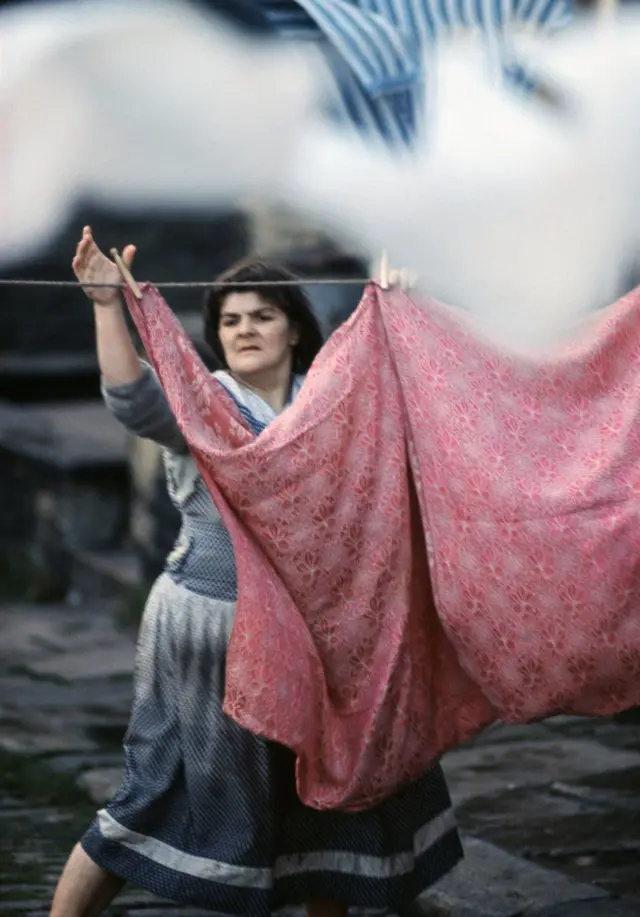 إمرأة تعلق ملابسها المغسولة على حبل للتجفيف