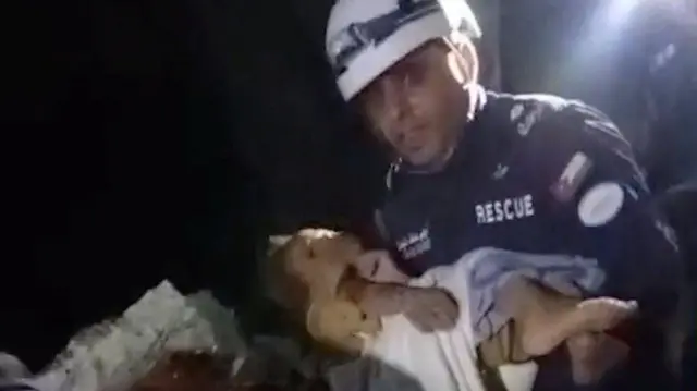 Uno de los rescatistas jordanos, con el niño en brazos, mientras lo saca de los escombros.