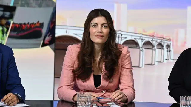 Laila Cunningham aparece el domingo con Laura Kuenssberg como panelista. Lleva una chaqueta rosa y mira a la cámara desde detrás de un escritorio.