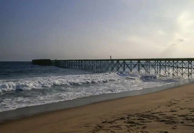 Une construction métallique qui sort de l'océan vers la plage.