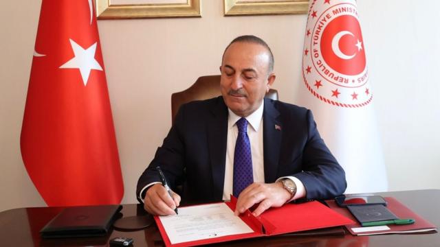Turkish Foreign Minister Mevlut Cavusoglu signing a document