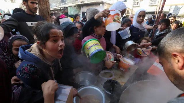 खान यूनिसमा सहायता संस्थाहरूले बाँडिरहेको खानाका लागि जुटेका बालबालिकाहरू