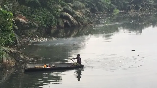 Man inside canoe dey pack pastic inside water