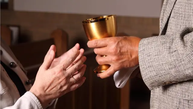 Catechist offers holy wine to churchgoer at communion