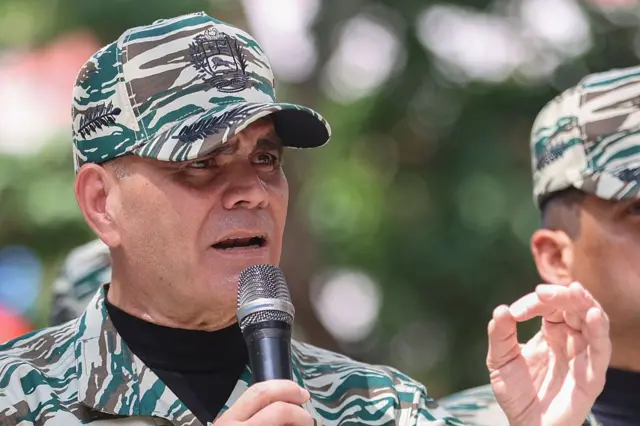 Vladimir Padrino López, vestido com uniforme de camuflagem militar, segura um microfone na mão.
