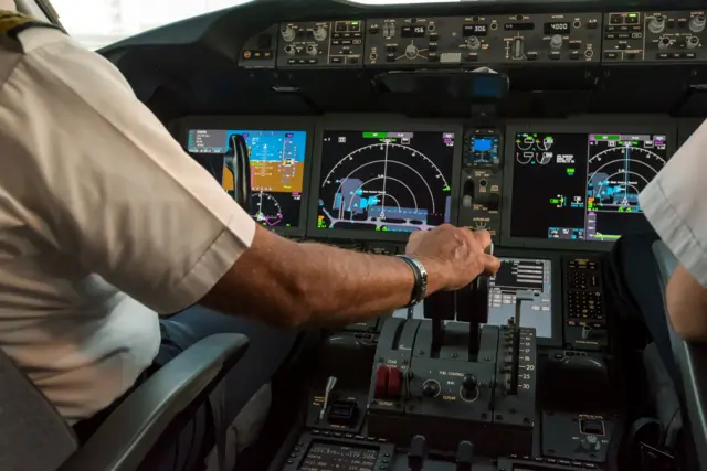 Cockpit de avião, com dois pilotos de costas