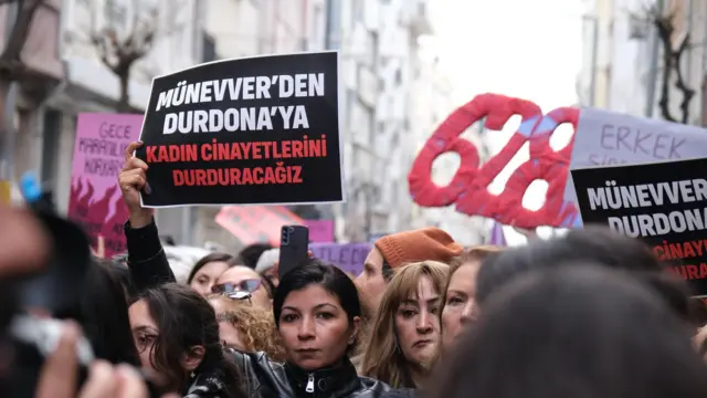 25 Ocak'ta Şişli'de düzenlenen protestoda elinde ''Münevver'den Durdona'ya'' yazan bir pankart taşıyan genç bir kadın. 