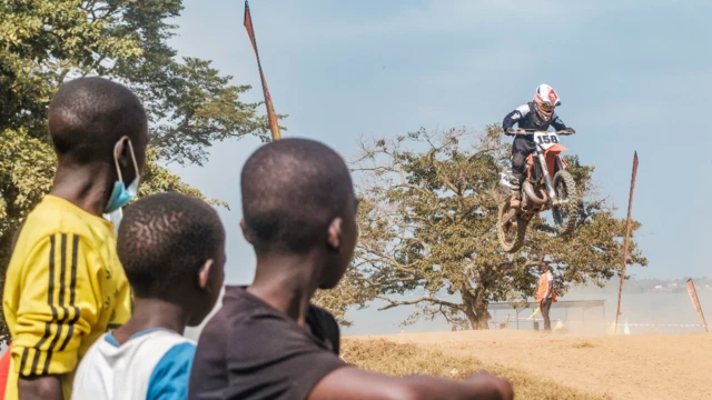 Des personnes regardent un pilote de motocross lors d'un rallye à Entebbe, en Ouganda - dimanche 30 janvier 2022