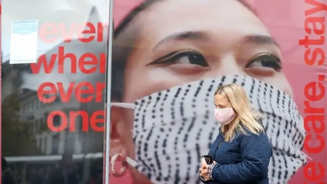 Mulher anda na rua usando máscaraManchester