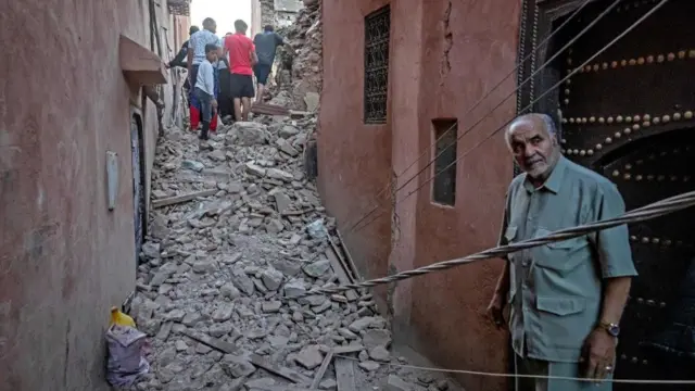 رجل ينظر بينما يتنقل السكان عبر الأنقاض في مدينة مراكش القديمة التي دمرها الزلزال في 9 سبتمبر 2023