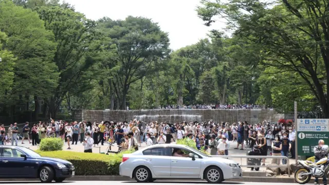 一边是抗议群众，但是在另一端的民众则是在等待航空自卫队经过。