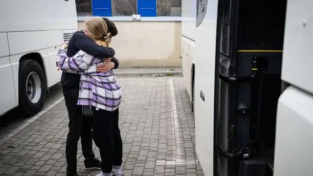 Молодые люди прощаются возле автобуса