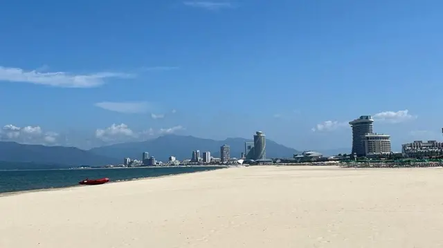 La playa con la arena clara, sin personas y de fondo se ven edificios