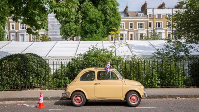 Fiat 500 bege clássico estacionado, com a bandeira do Reino Unido
