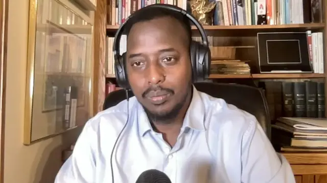 Um homem em um escritório usa fones de ouvido e fala ao microfone