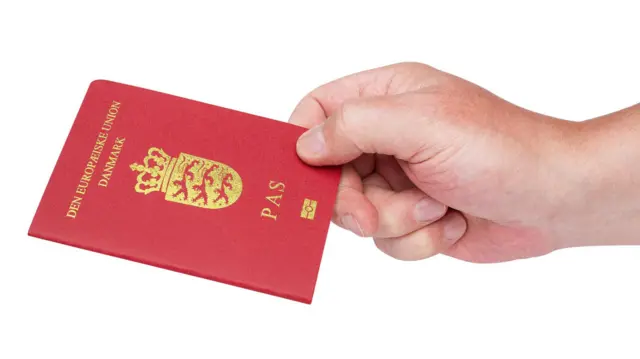 Mão segura um passaporte dinamarquês
