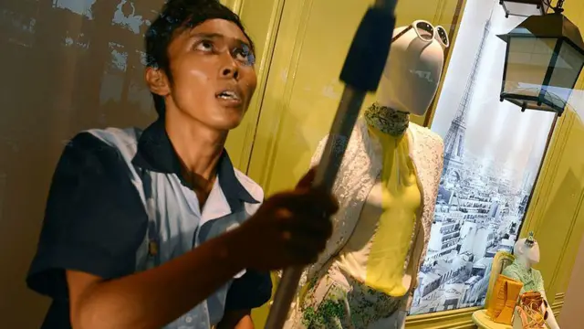 Ilustrasi pramukantor sedang membersihkan kaca etalase.