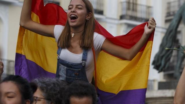 Girl in protest crowd carrying red, yellow, purple Republican flag