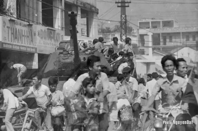 Khoảng 14 giờ chiều ngày 30/4/1975 tại ngã tư Phú Nhuận. Chiếc xe tăng M48 của lính VNCH bỏ lại trên đường còn nguyên súng đạn trên xe, một số thanh niên và trẻ em tò mò leo lên nghịch phá. Trên đường xuất hiện những lá cờ Giải Phóng xanh đỏ với sao vàng được gắn trên xe máy của hai người đàn ông đang di chuyển. 
