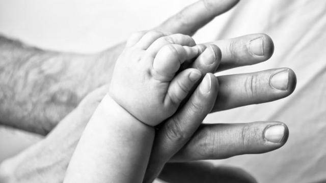 A baby`s hand with a man`s hand