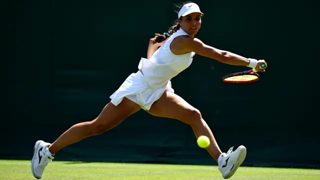 Tenista atinge a bola com sua raquete em quadra de Wimbledon