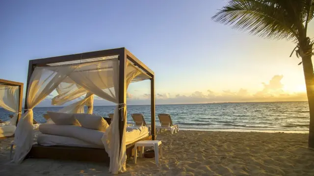 Una cama con dosel sobre una playa