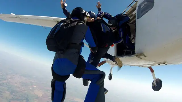 Três paraquedistas saltando de um avião