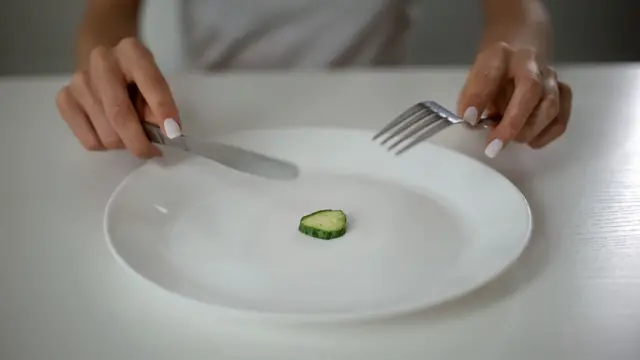 Una mujer comiendo un pedazo de pepino