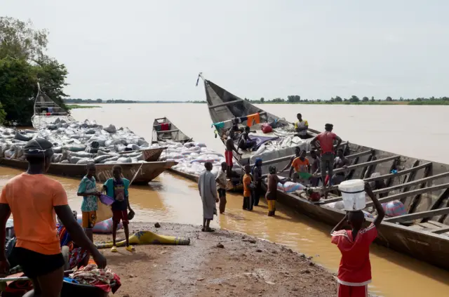 Des personnes déchargent les cargaisons des bateaux du Bénin sur les rives du fleuve Niger pour les transporter sur des camions et les acheminer vers différentes villes de Gaya, au Niger, en 2023.