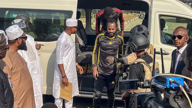 अपहरणकर्ताओं की कैद से छूटने के बाद एक सरकारी मकान में लाए जाते नाइजीरियन कैथोलिक स्कूल के शिक्षक