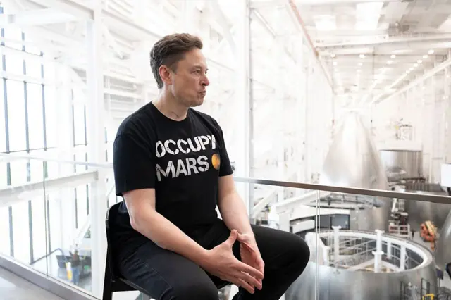 Elon Musk con uma camiseta que tem "Occupy Mars" escrita 