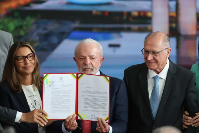 Lula, Janja e Geraldo Alckmin segurando documento com o veto assinado pelo presidente