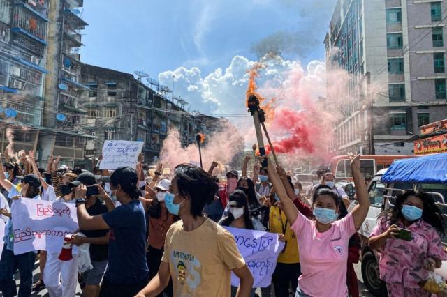 仰光一場反軍政府示威上婦女舉起標語牌、緊急信號棒和火把前行（14/7/2021）