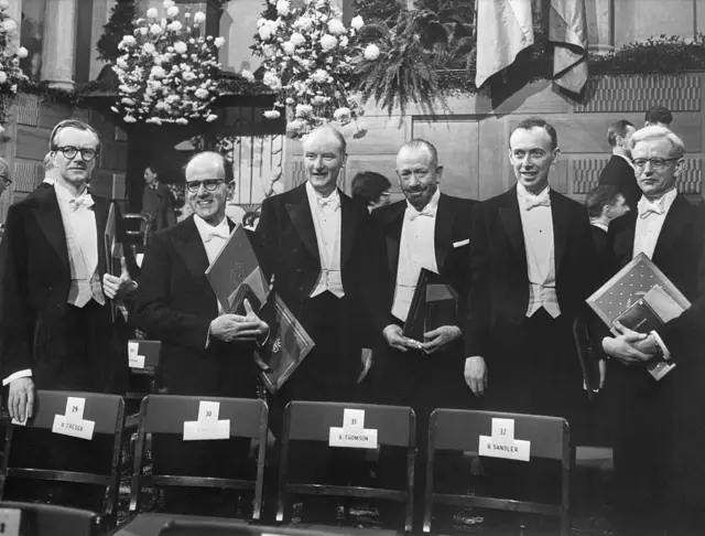 Vestidos de gala, los ganadores de los Premios Nobel de 1962 exhiben sus diplomas tras las ceremonias celebradas en la Sala de Conciertos de Estocolmo. De izquierda a derecha: el profesor Maurice H. Wilkins (Medicina); el Dr. Max Perutz (Química); el Dr. Francis Crick (Medicina); el escritor John Steinbeck (Literatura); el profesor James D. Watson (Medicina); y el Dr. John Kendrew (Química).