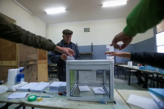 People point at the ballot box as a man walks to cast his vote during the local elections, in Algiers, Algeria November 27, 2021