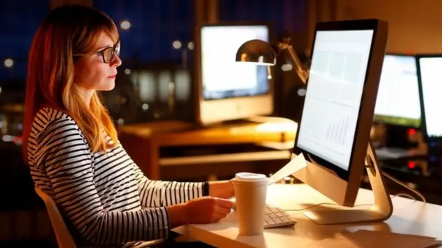 موظفة تجلس أمام شاشة كمبيوتر