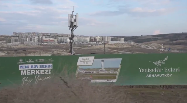 Dursunköy Mahallesi'ndeki, Emlak Konut GYO'ya ait Yenişehir Evleri projesi. Arkada inşaatlar var. Öndeki tabelada ise Yenişehir Evleri yazıyor. 