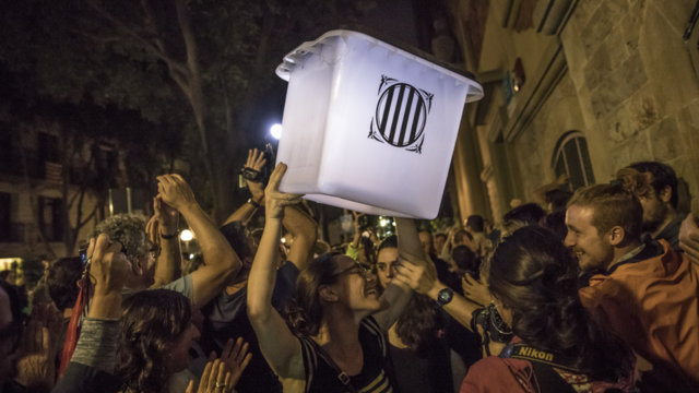 An election official carries an empty polling box out of the polling station after the counting had finished for the referendum vote on October 1, 2017 in Barcelona