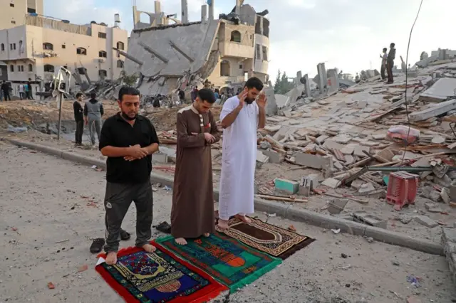 In Beit Lahia in the northern Gaza Strip, Palestinian Muslims perform the morning Eid al-Fitr prayer amid destroyed buildings following Israeli airstrikes (above and below)