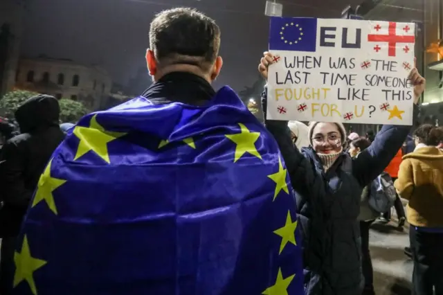 Протестующий с флагом Европы и девушка с плакатом: "ЕС, когда последний раз кто-то так боролся за тебя?" на протесте в Тбилиси 