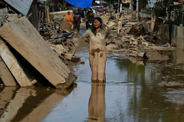 Seorang perempuan berdiri di tengah reruntuhan akibat banjir di Aceh, November lalu.